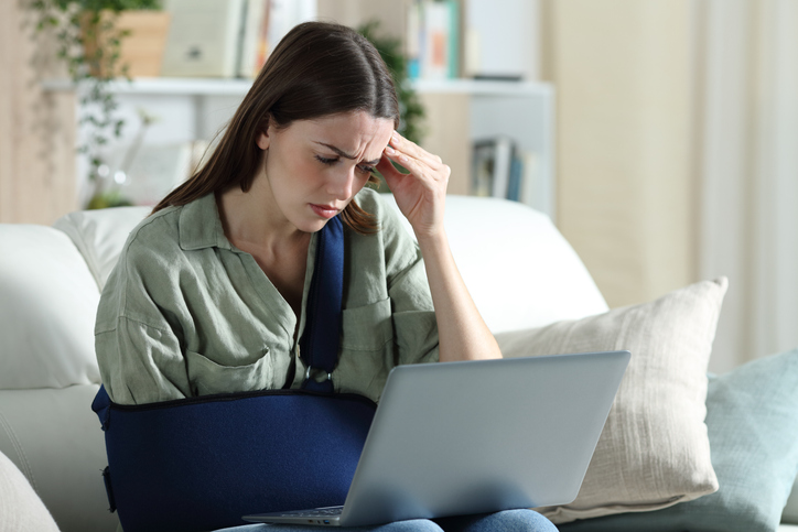 Young adult in cast looking disapprovingly at computer