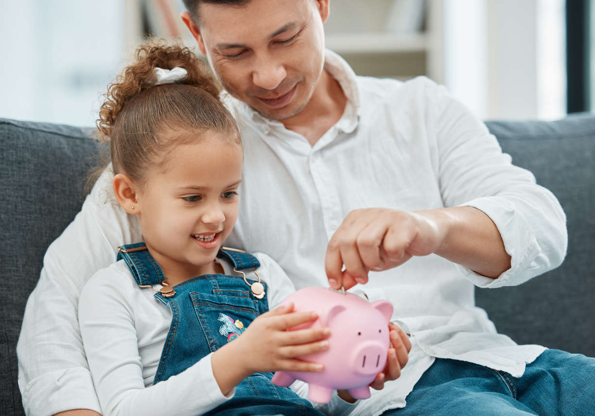 Father and daughter putting money into a piggy bank