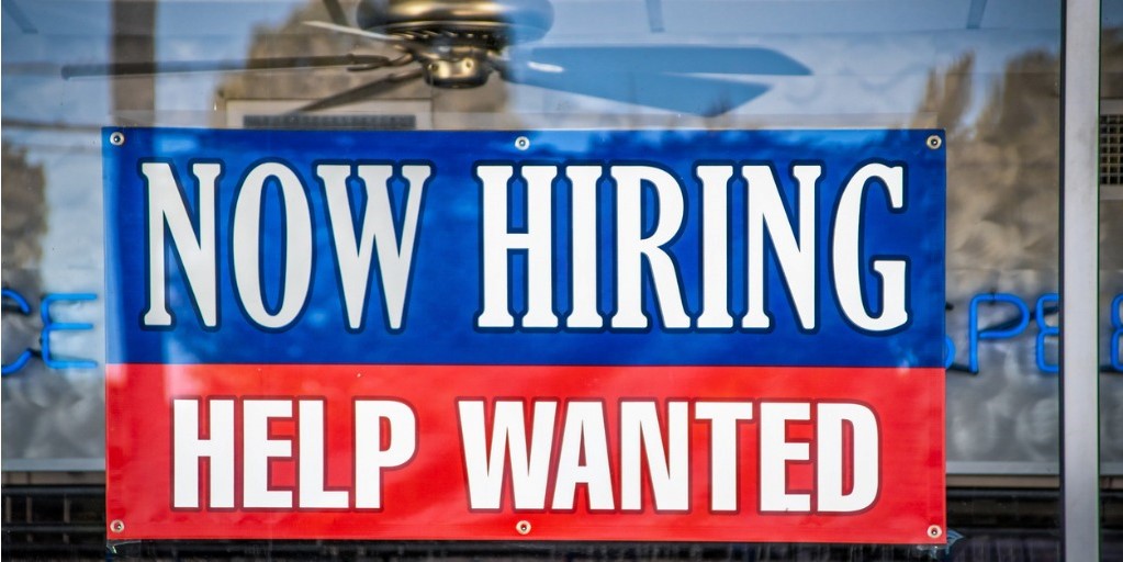 Now Hiring Help Wanted Sign in window of business with 