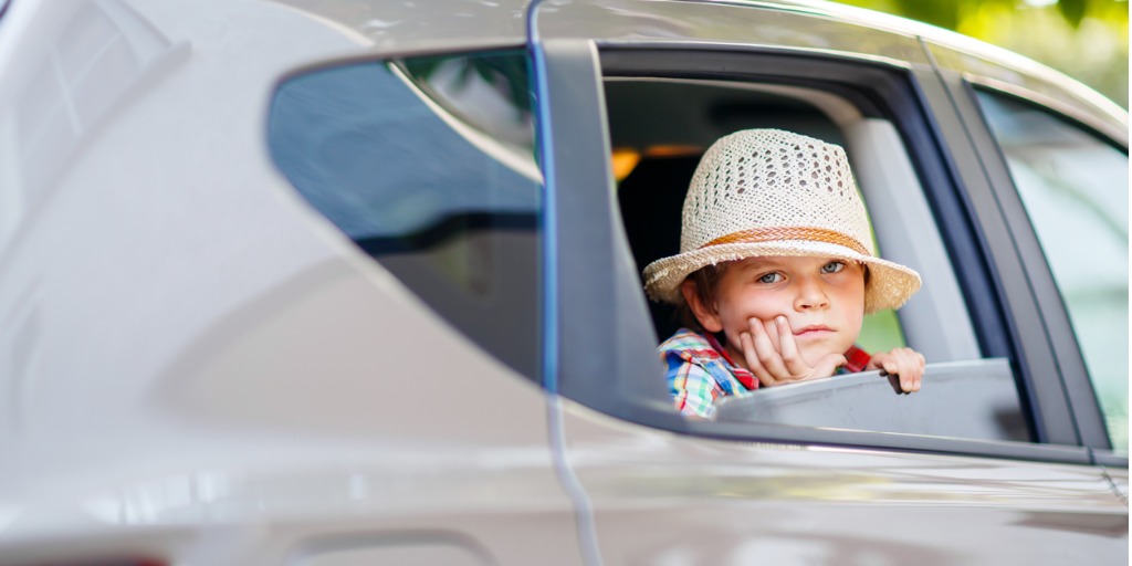 Sad little kid boy sitting in car in traffic jam during