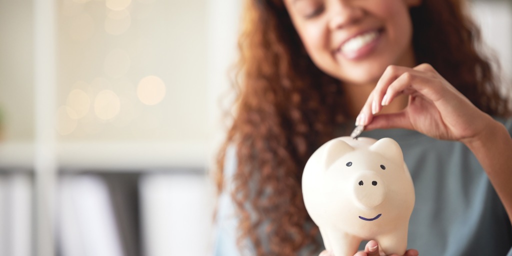 One happy young mixed race woman holding a piggybank an