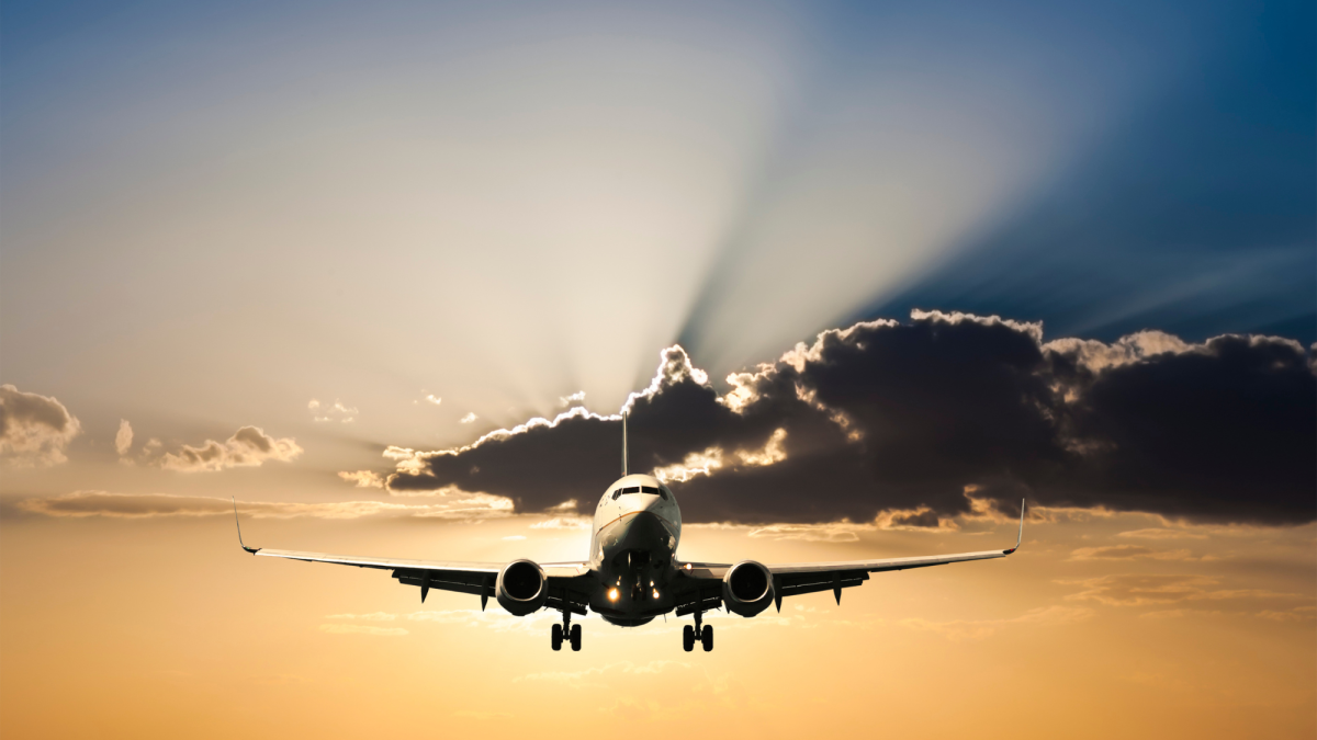 Airplane in a golden sky with clouds behind