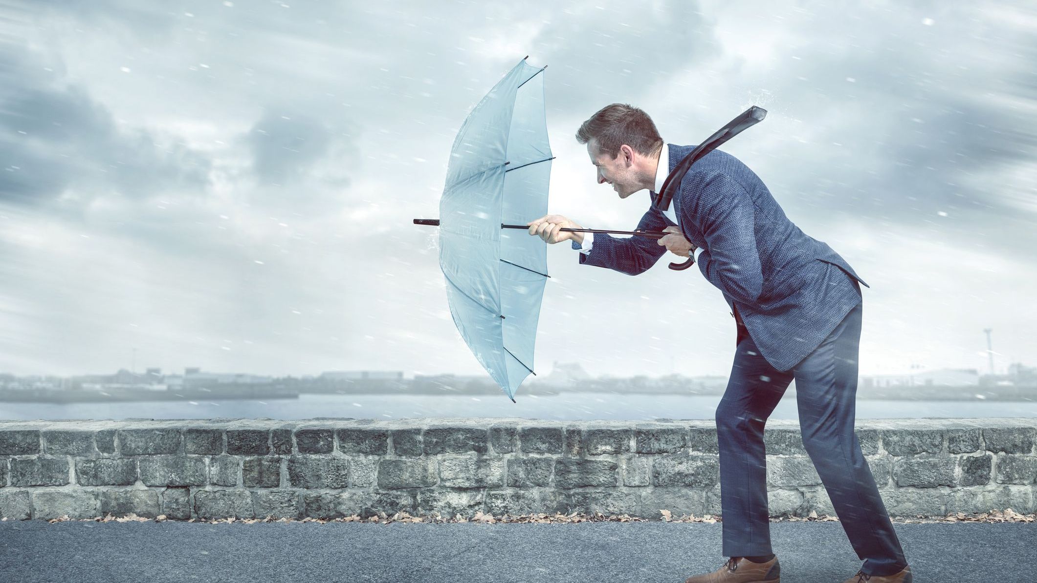 A young business man holding an umbrella to shield hims