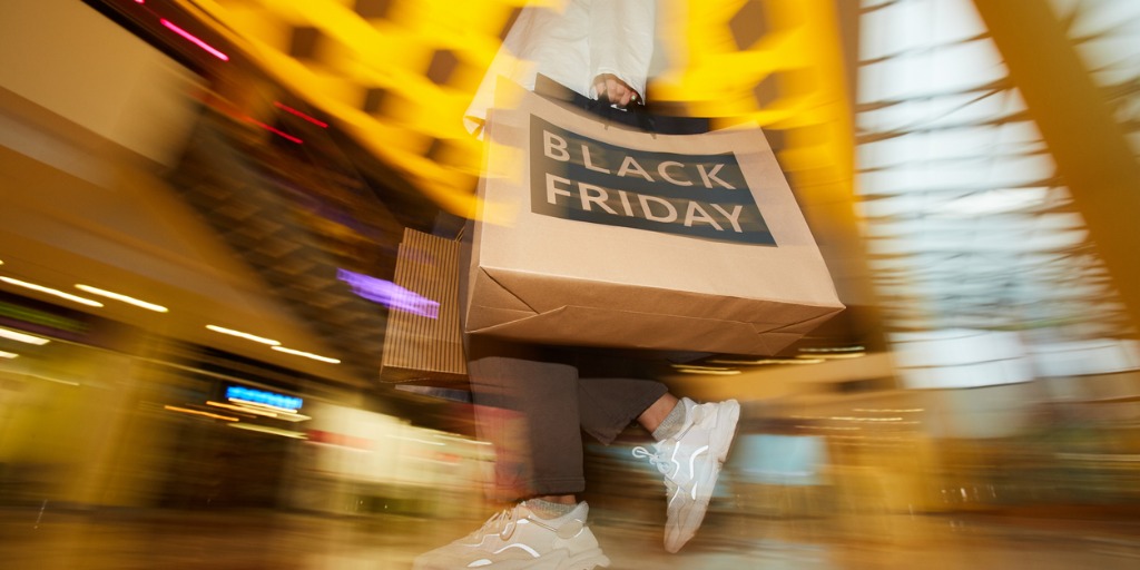 Blurred motion of shopaholic carrying shooping bags whi