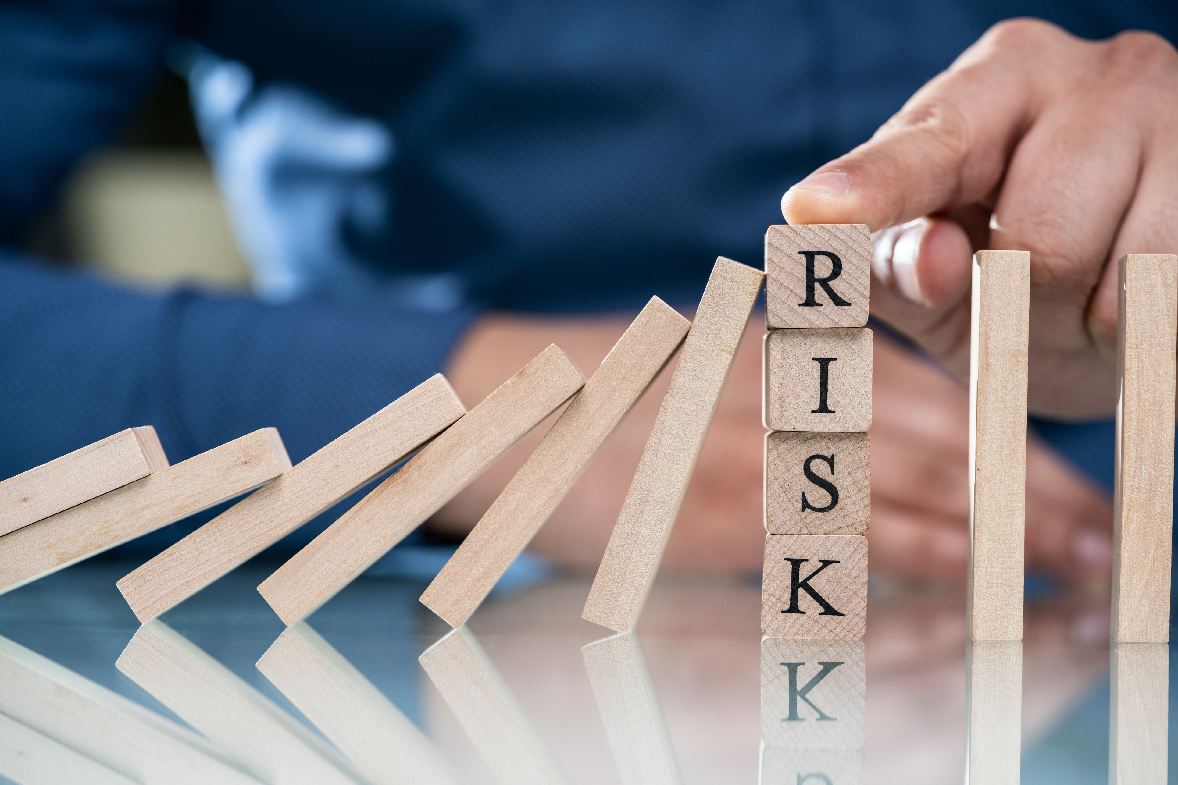 Businessperson's Finger Over Risk Wooden Blocks Stoppin