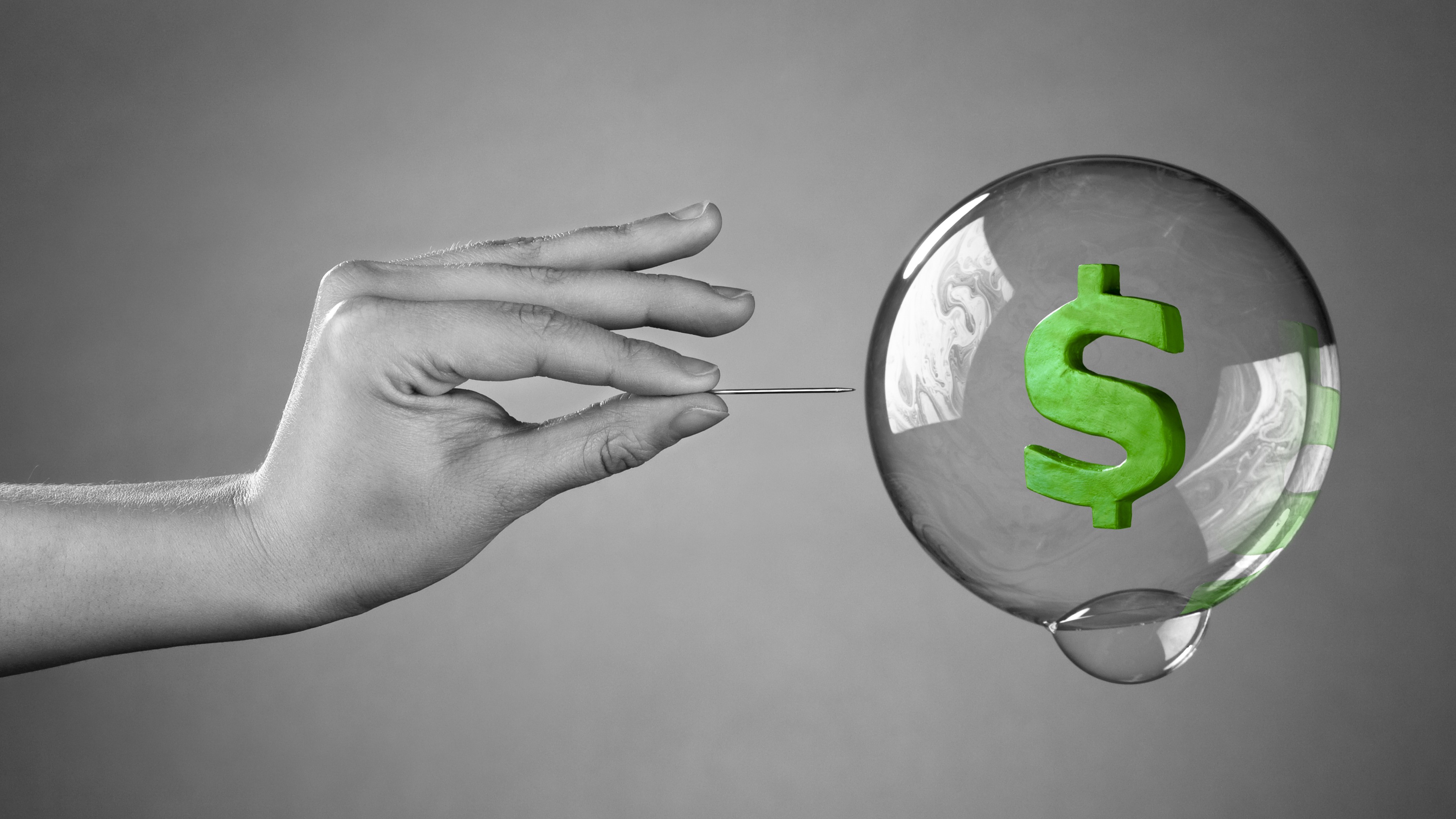 A hand about to burst a money bubble with a pin. Metaph