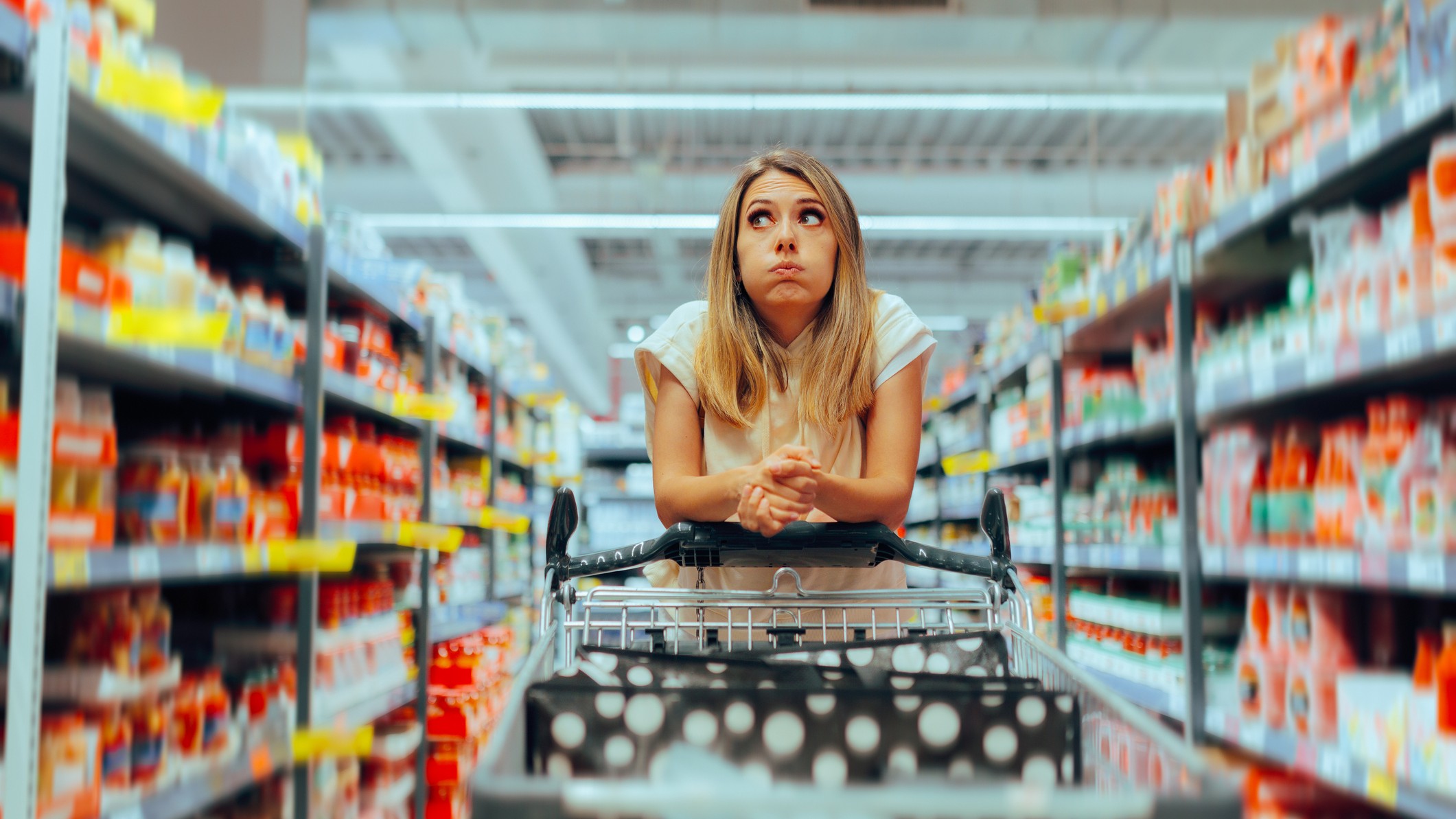 woman behind a shopping cart in a store contemplating h