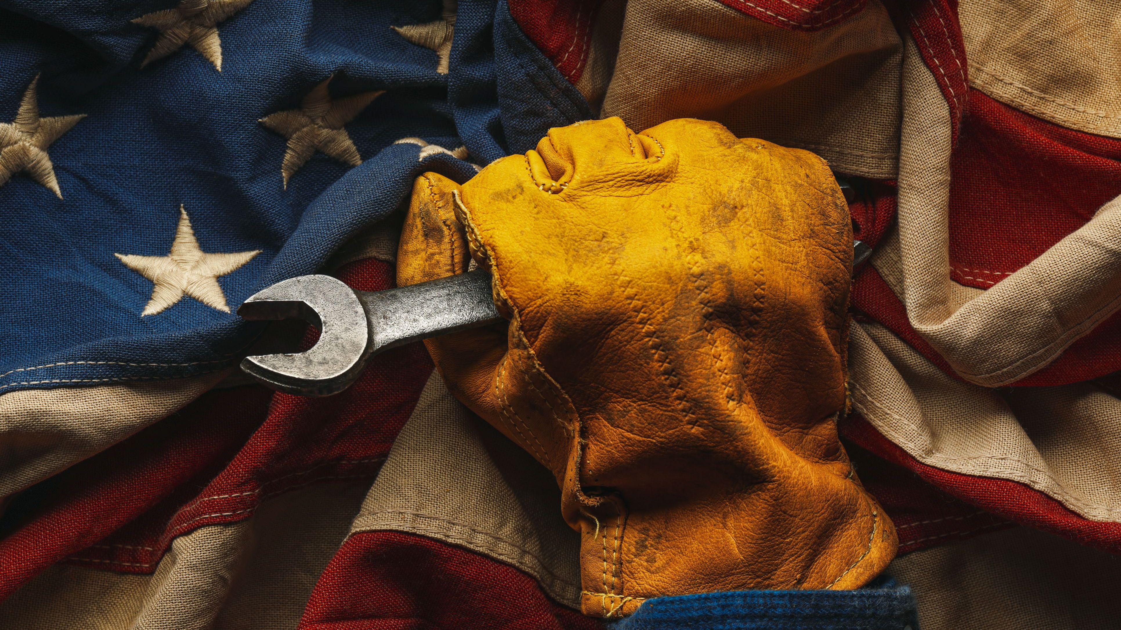 Worn work glove with wrench and the American flag. Symbolic of blue collar workers, USA manufacturing, pride in products Made in United States of America, or celebrate Father's day or US Labor Day.