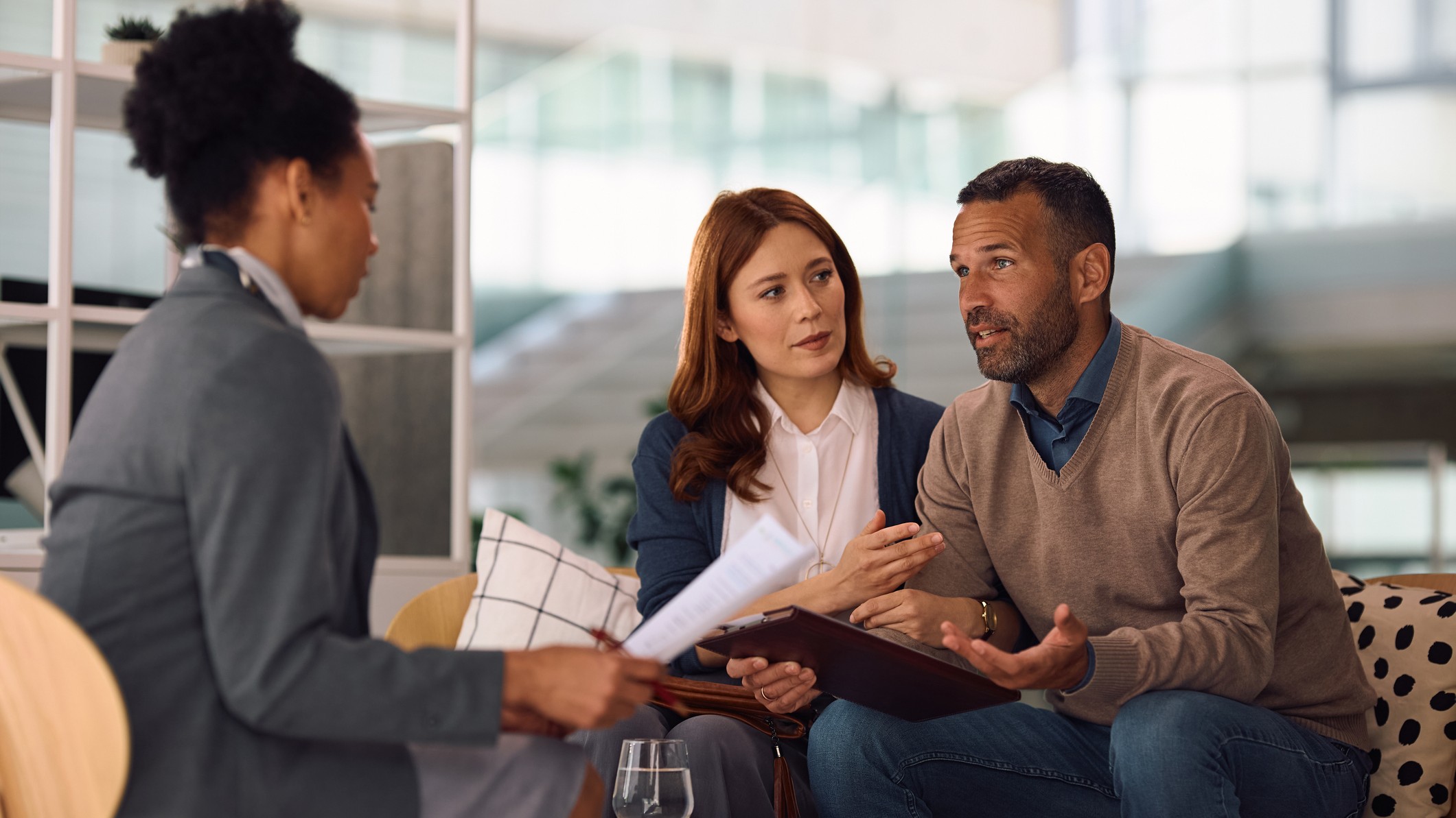 Mid adult couple talking to their financial advisor while analyzing paperwork in the office. 