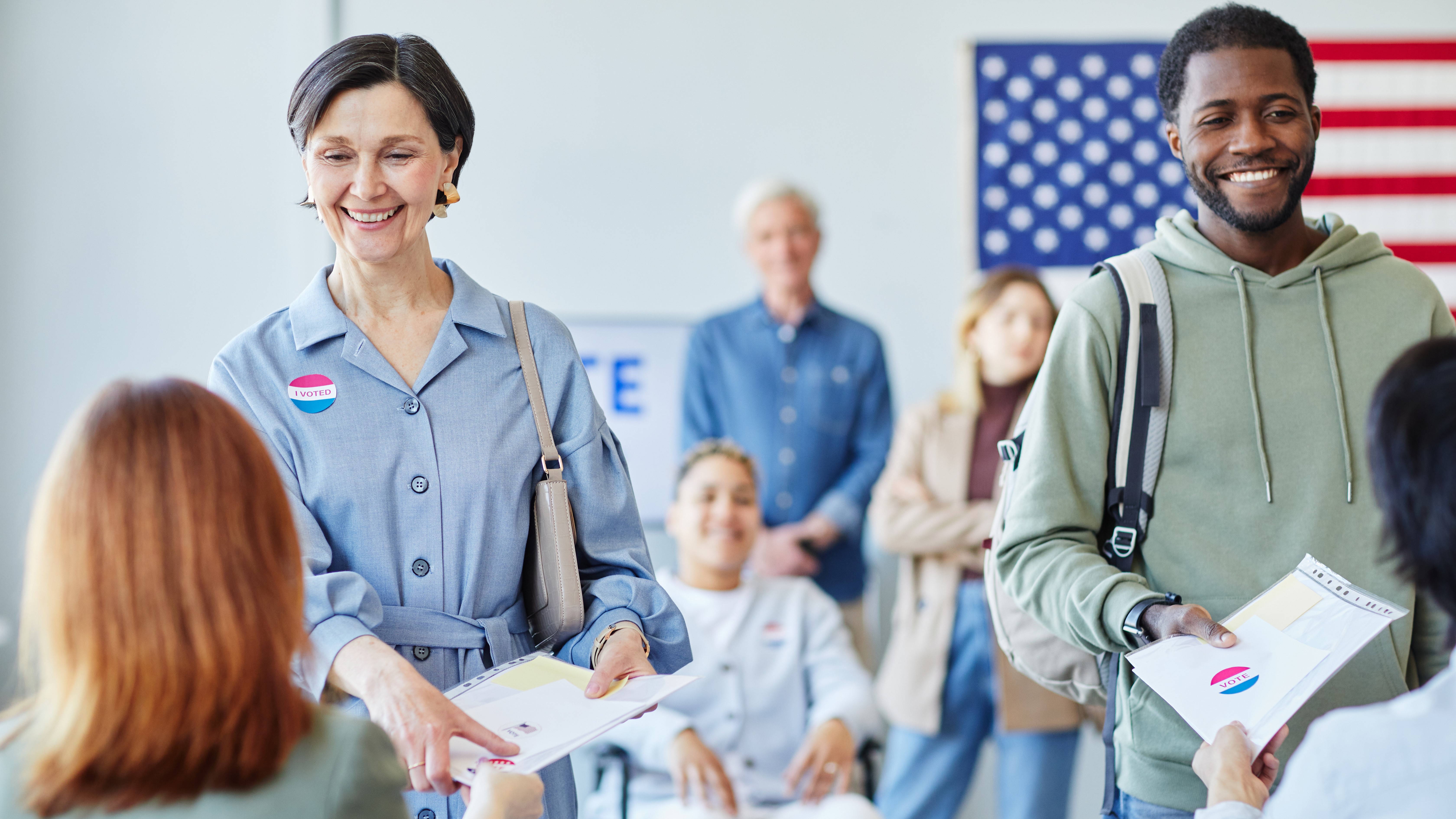Front view portrait of two smiling people receiving paperwork for voting on election day 